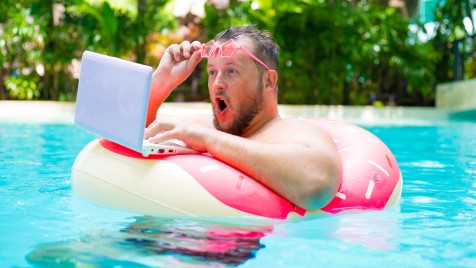 Mann mit Laptop auf einem Schwimmreifen im Wasser Mann mit Laptop auf einem Schwimmreifen im Wasser
