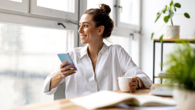 Frau sitzt mit Handy an Tisch