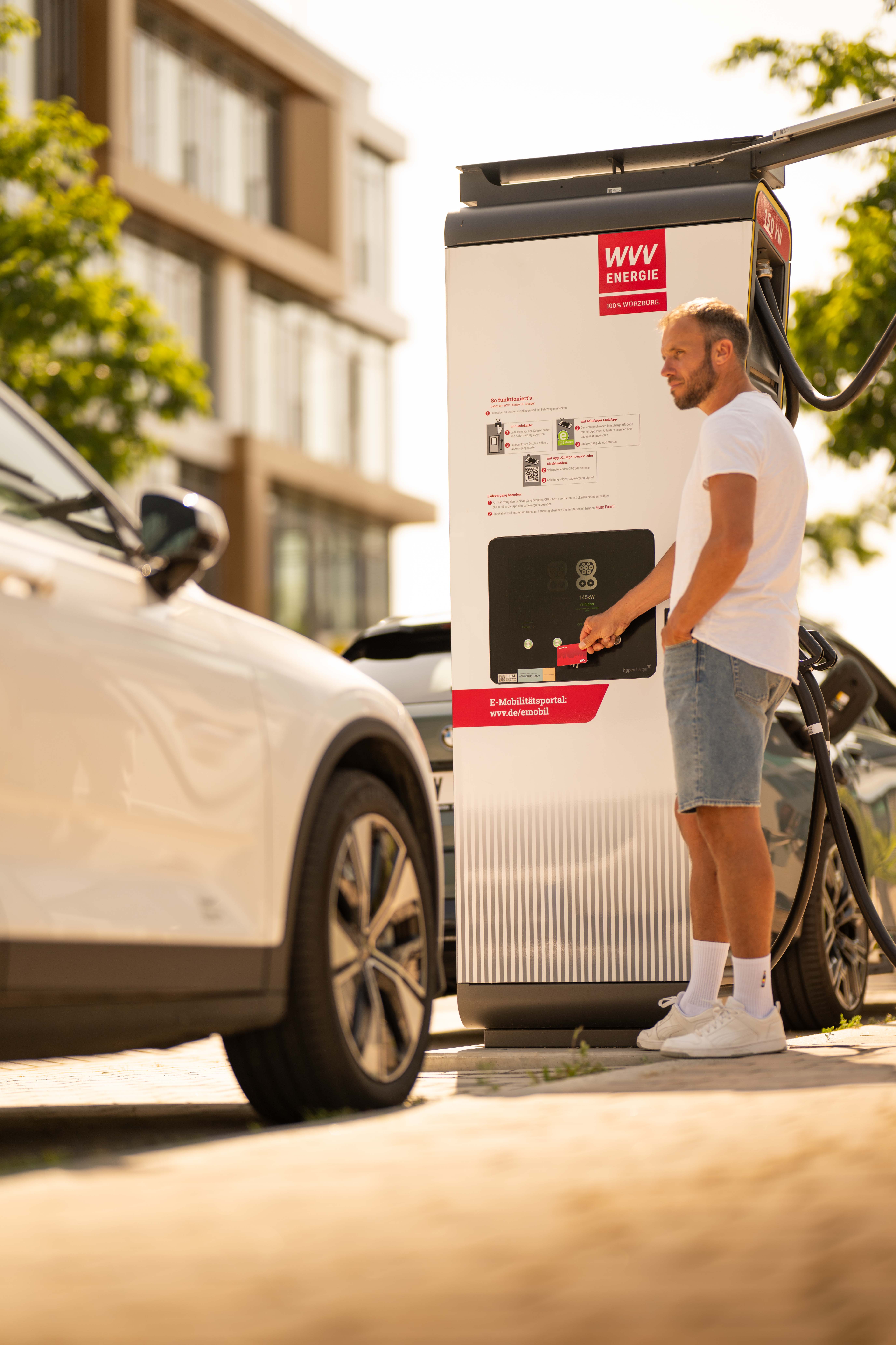 Auto und Mann vor E-Ladesäule