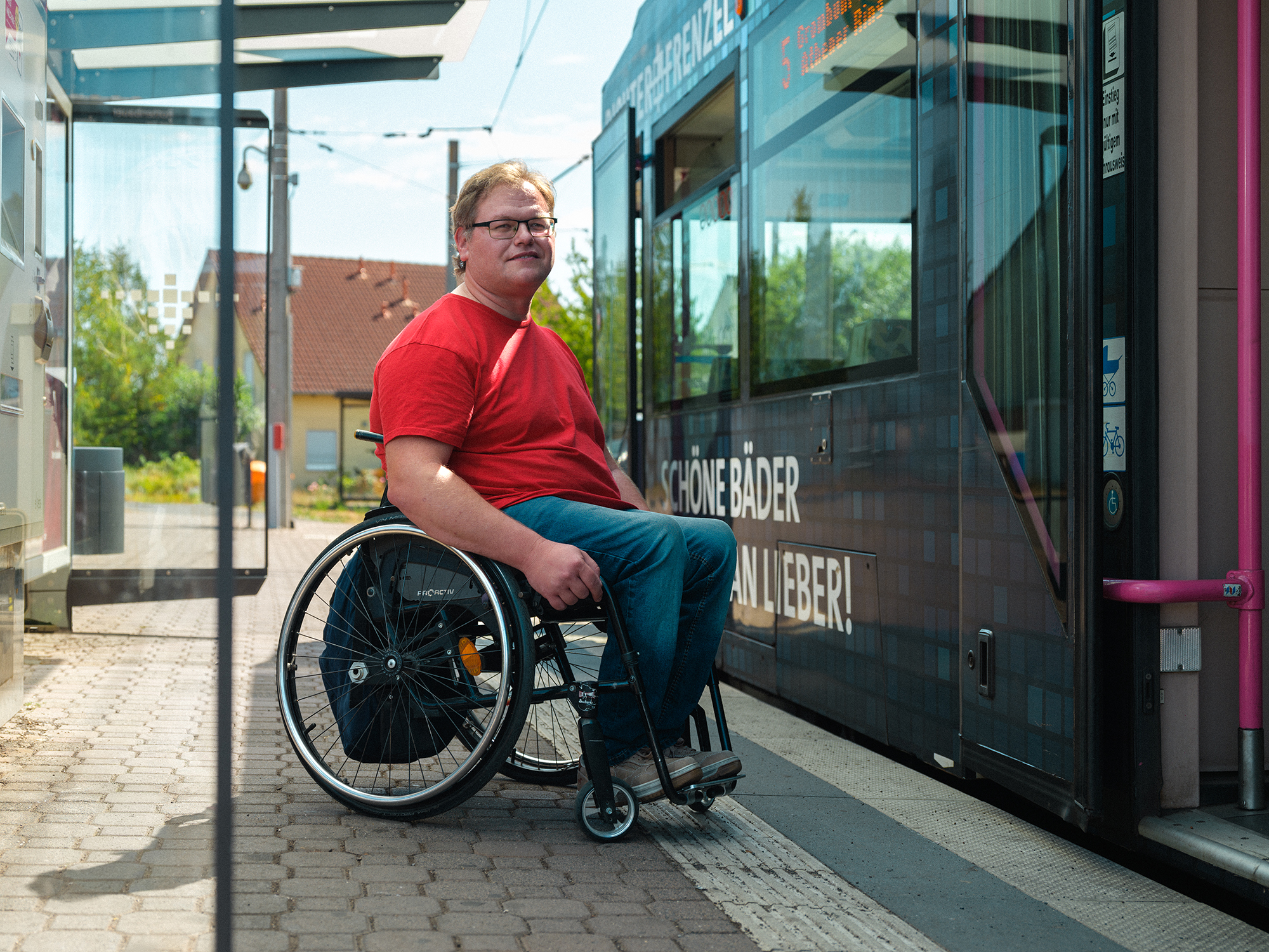 Rollstuhlfahrer an Haltestelle Straßenbahn