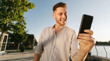 Mann schaut glücklich auf Smartphone