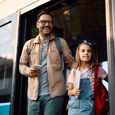 Papa und Tochter steigen aus Bus aus